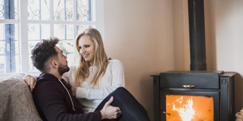 Couple sur un canapé à côté d'un poêle à bois.